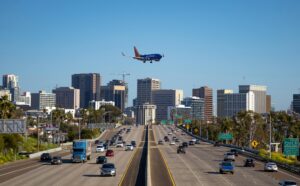 Airplane approaching San Diego airport over busy city freeway and skyline.